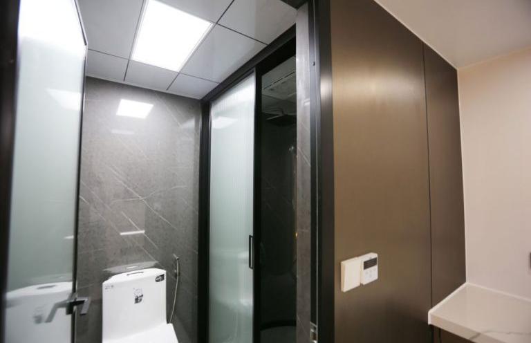 Ванная в LUBAN CABIN K50 featuring a modern toilet, shower enclosure, and dark gray walls