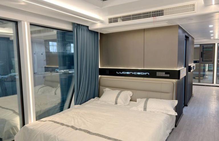 Современная спальня в LUBAN CABIN Номер K70 с большой кроватью с фирменным изголовьем и элегантными шторами.