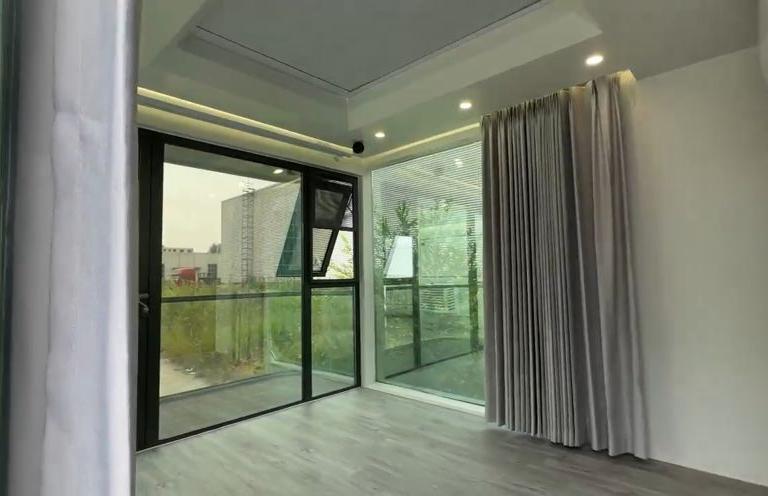 Room in LUBAN CABIN K30 featuring large sliding glass doors leading to a balcony, and elegant gray curtains.